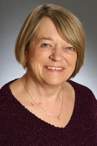 a woman smiling wearing a purple blouse